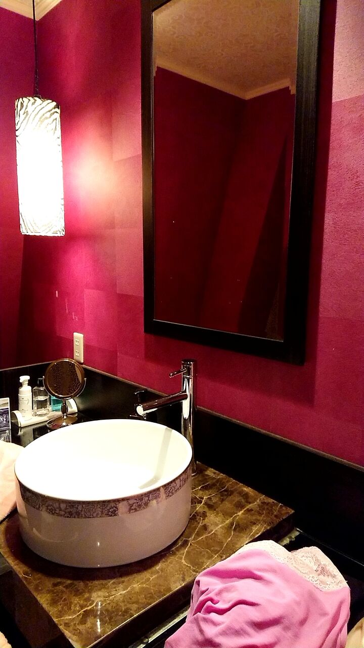 ホテルの洗面台に脱ぎ捨てられたピンクの衣類とシャワーの音が聞こえてきそうな室内